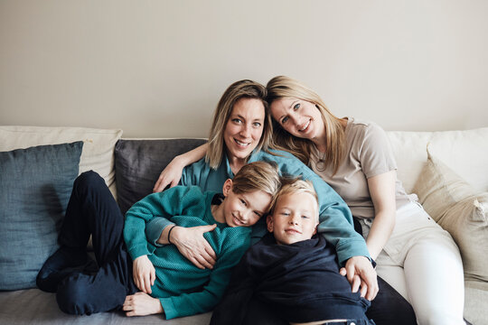 Portrait of lesbian mothers with sons sitting together on sofa at home