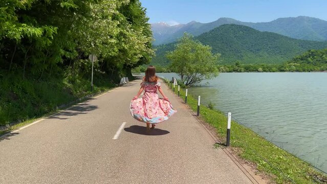 Inspired runaway alone romantic boho chic girl in long dress runs along road along river overlooking the mountains