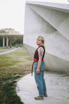 Side view of non-binary person standing near wall at park