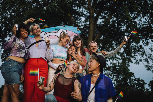 Happy friends enjoying during LGBTQIA rights parade against tree