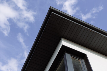 The dark slope of the roof of the house on the background of the sky.