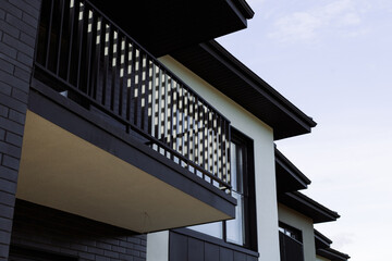 Metal black railing of the balcony on the background of the cottage.