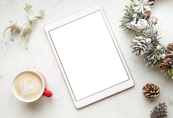 Christmas decorations and tablet on white concrete background.