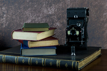 Old Books and Old Folding Camera on a Varnished Wooden Surface