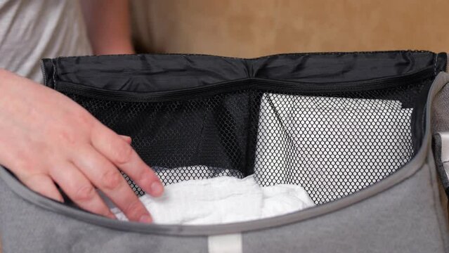 Female prepares big bag for walking with baby to park. Parent takes care of child and wants to prepare necessary stuff putting toys and food for kid, closeup