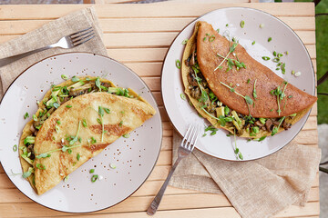 Vegan pancakes filled with mushrooms, pea sprouts and avocado. Healthy breakfast for two persons on the wooden table.