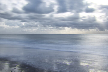 Horizontal minimalistic view on the sea on a cloudy day. Abstract seascape background with soft blur and copy space
