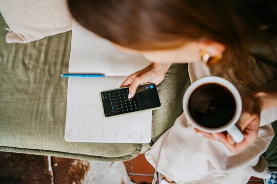 Entrepreneur Using Calendar On Smart Phone Holding Coffee Cup At Studio