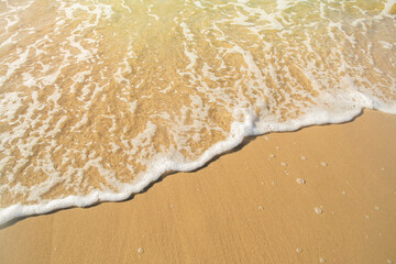 Close-up of a beach with a calm transparent wave. Romantic sea coast with golden sand.