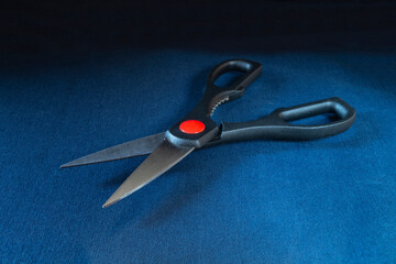 Metal scissors with plastic handles on a blue table