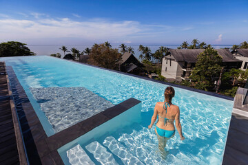 luxury vacation, woman entering rooftop infinity pool in luxurious hotel resort