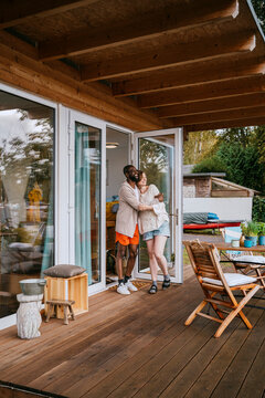 Multiracial couple embracing each other while standing on porch near doorway