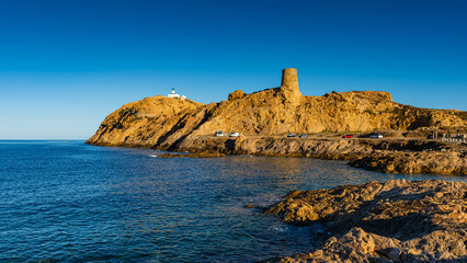 Fototapeta na wymiar The old lighthouse and the Genoese tower on the rocky Pietra peninsula in the L'Ile-Rousse commune of France on Corsica, France