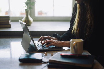 Hands of female entrepreneur typing on laptop at table in restaurant