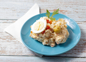 Tapa of russian salad on a blue plate on a wooden background