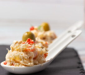 Close-up of russian salad. Typical Spanish tapa in white ceramic spoons.