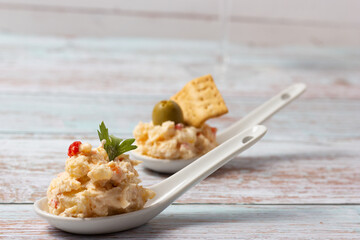 Russian salad appetizers in ceramic teaspoons on a wooden base
