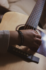 Close-up of woman's hand playing a chord on an acoustic guitar.