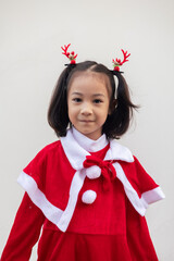 Portrait shot of adorable asian kid girl with red sweater for Christmas costume on white background shows concept of happiness celebration. It is the emotional face expression of enjoyment.