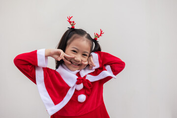 Portrait shot of adorable asian kid girl with red sweater for Christmas costume on white background shows concept of happiness celebration. It is the emotional face expression of enjoyment.