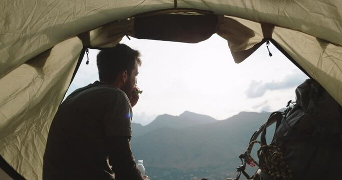 man is a tourist, backpacker, freelancer is sitting drinking refreshing water and eating a sandwich resting on the top of the mountain. Health care, authenticity, a sense of balance and tranquility.