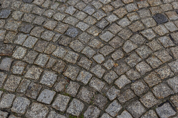Granite dirty paving stones in the city. Road from paving stones for background and texture. The old road of granite paving stones