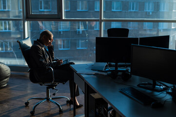 Business woman with short hair sits by the window and writes on a digital tablet with a stylus pen