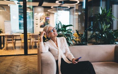Cheerful elderly businesswoman relaxing in office