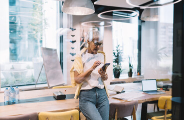 Senior woman with smartphone in meeting room in office