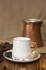 Turkish coffee cup, coffee beans and a coffee pot made of copper on wooden background
