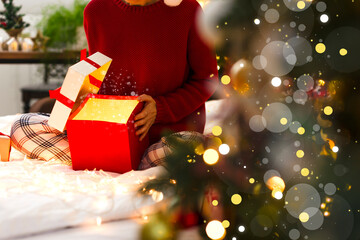 The girl opened a Christmas gift with a bright light. Beautiful festive photo, Christmas tree, blurred lights, highlights, beautiful defocus. The concept of Christmas and New Year