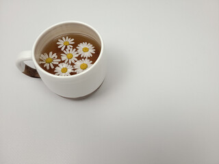 Chamomile tea in a white clay cup on a light background