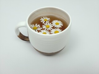 Chamomile tea in a white clay cup on a light background