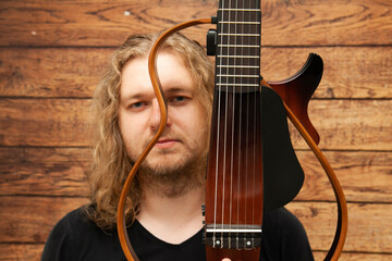 A man with long blond hair holds an electric guitar in his hands. Solo Guitarist