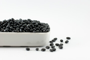 Fototapeta na wymiar Black beans are housed in white ceramic vessels and placed on a white floor, selective focus, space for text.