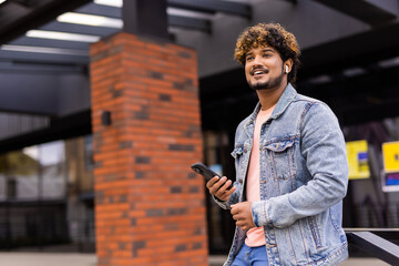 Smiling indian man calling on smartphone on city street