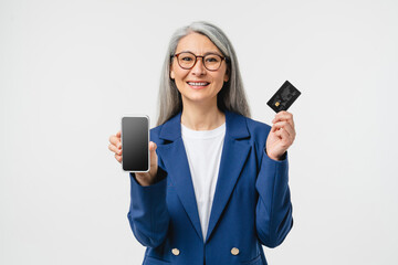 E-banking e-commerce. Mature businesswoman bank manager employee using credit card for online shopping, paying domestic bills, receive payment, salary showing cellphone mockup screen isolated in white