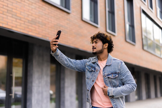 Excited young indian man taking a selfie with phone on the street