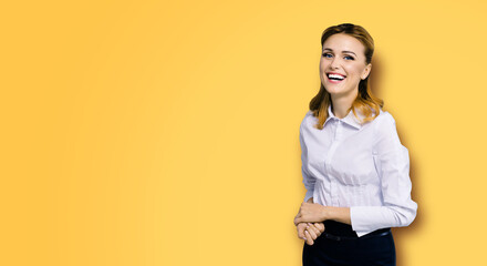 Happy smiling attractive businesswoman, with copy space area for some slogan or text. Confident blond woman in white shirt, orange yellow color background. Business concept.