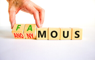 Famous or anonymous symbol. Concept word Famous and Anonymous on wooden cubes. Businessman hand. Beautiful white table white background. Business famous or anonymous concept. Copy space.