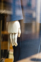 Articulated bionic hand, part of a robot dressed in a suit, behind glass