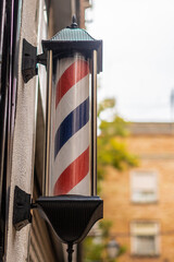 Barber shop pole outdoors, on the wall of a house.