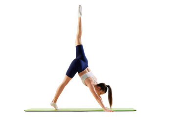 Portrait of young sportive woman training, doing stretching exercises, rising leg up, body down isolated over white background. Concept of sport, fitness, health
