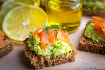 Toasts with avocado and smoked salmon on the wooden plate