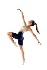 Portrait of young sportive woman training, doing full body exercises, standing on tiptoe isolated over white background. Concept of sport, fitness, health