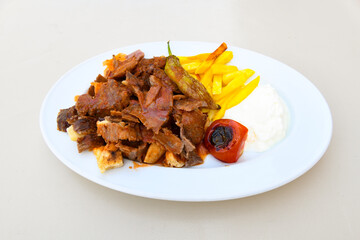 Turkish and Arabic Traditional Ramadan doner kebab with tasty tomato sauce and rice or turkish pilav in white plate on wood table background. ( Pilav ustu doner)
