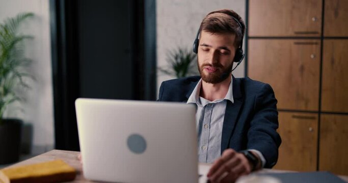 Male top manager of company is talking through online video link with job seeker. Bearded man gesticulates and tells future employee about the job. A relaxed interview for a good and profitable work.