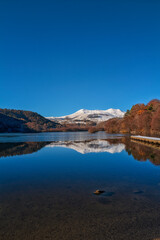 Obraz premium reflet dans le lac Chambon, montagnes enneigées et ciel bleu