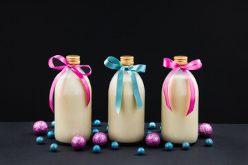 Homemade eggnog in bottles with pink and blue balls on dark background