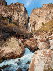 Amazing landscape view of big mountain waterfall known as Sultan, autumn grass, big stones and high rocks as a background. Caucasus nature, Jila Su Elbrus region, Kabardino-Balkaria.